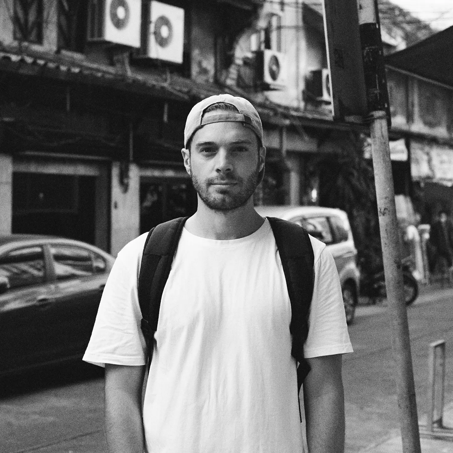 A photograph of Ross, from Tidal Wave, in the street wearing a baseball cap.